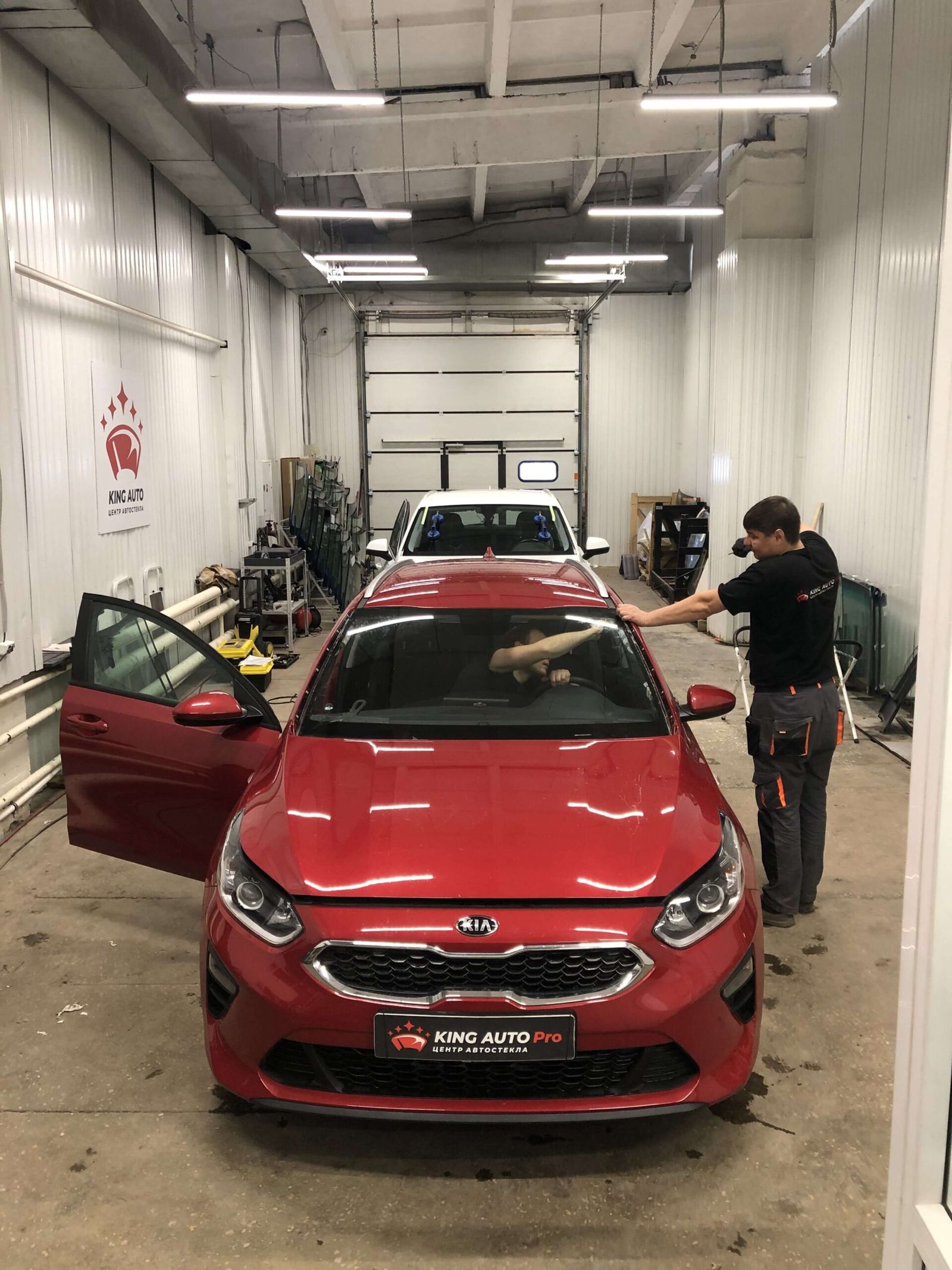 Мастер у красного Kia в боксе KING AUTO Pro